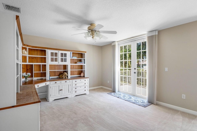 unfurnished office featuring french doors, a ceiling fan, light carpet, and visible vents