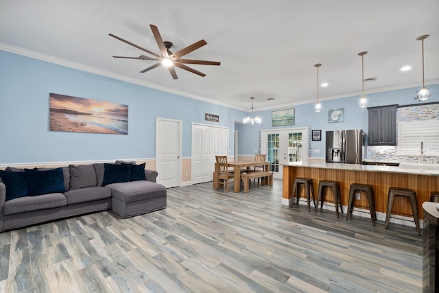 living room featuring hardwood / wood-style floors, ceiling fan, crown molding, and french doors