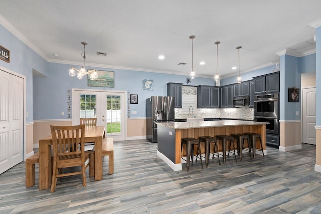 kitchen with light stone countertops, a center island, french doors, hanging light fixtures, and stainless steel appliances