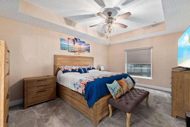 carpeted bedroom with a raised ceiling, ceiling fan, and a textured ceiling