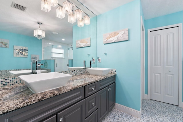 bathroom featuring tile patterned flooring, a notable chandelier, decorative backsplash, a shower with door, and vanity