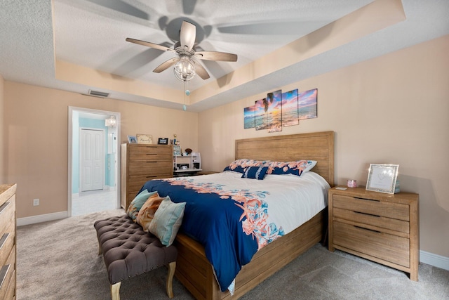 carpeted bedroom featuring a raised ceiling, a textured ceiling, and ceiling fan