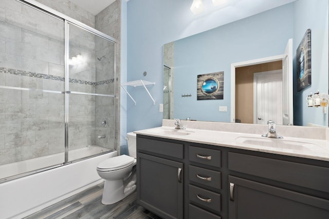 full bathroom with toilet, vanity, bath / shower combo with glass door, and hardwood / wood-style floors