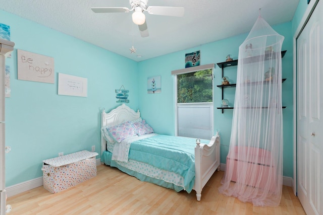 bedroom featuring a textured ceiling, hardwood / wood-style flooring, a closet, and ceiling fan