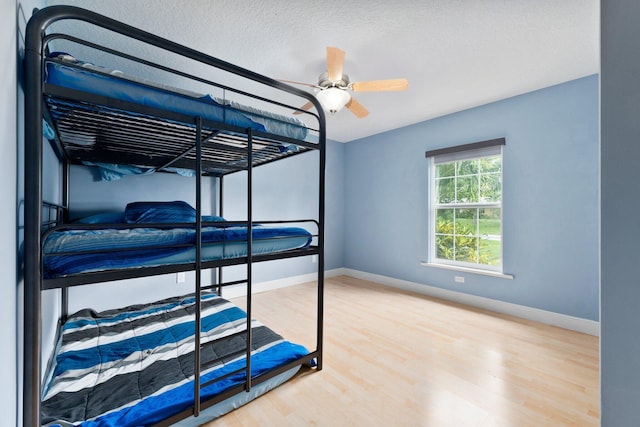 bedroom with wood-type flooring, ceiling fan, and a textured ceiling