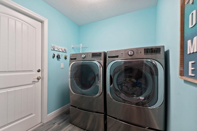 clothes washing area with independent washer and dryer, a textured ceiling, and hardwood / wood-style flooring