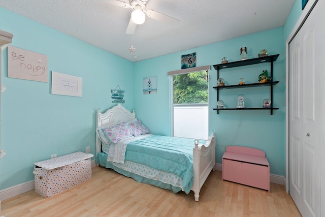 bedroom with ceiling fan, a textured ceiling, a closet, and light hardwood / wood-style flooring