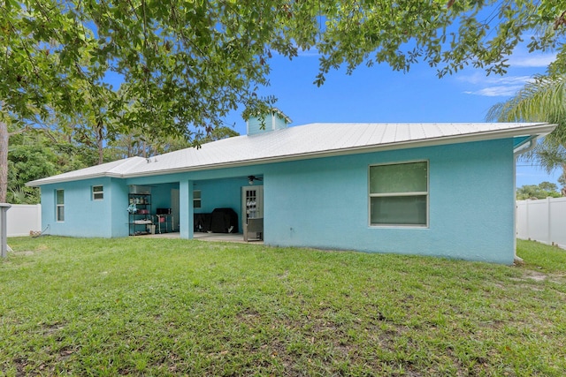 rear view of property featuring ceiling fan, a patio, and a lawn