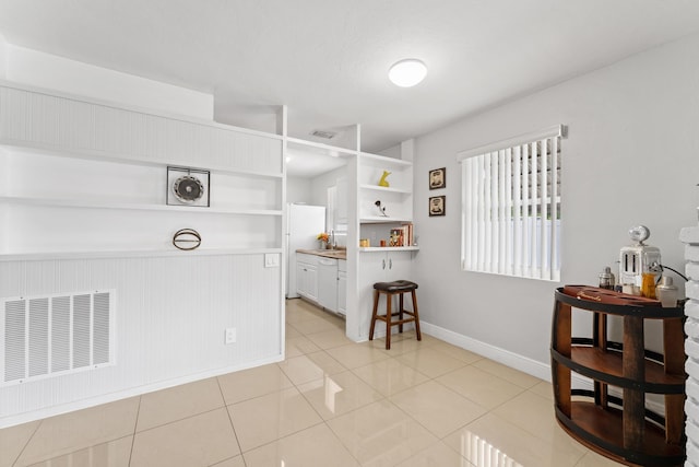 interior space featuring light tile patterned flooring, built in features, and white cabinets