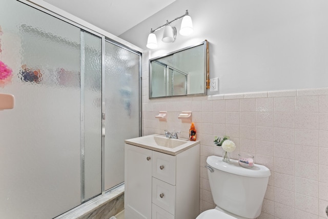 bathroom with vanity, tile walls, decorative backsplash, toilet, and a shower with door