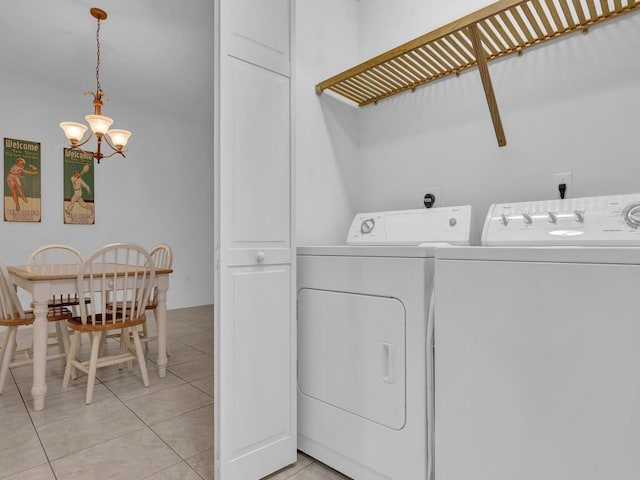 washroom with washing machine and clothes dryer, a notable chandelier, and light tile patterned floors