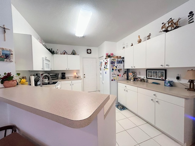 kitchen featuring white cabinetry, a kitchen breakfast bar, kitchen peninsula, a textured ceiling, and white appliances