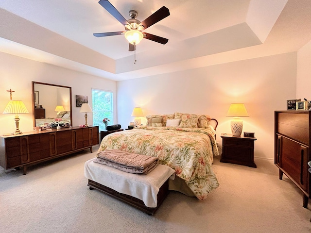 bedroom featuring light carpet, ceiling fan, and a raised ceiling