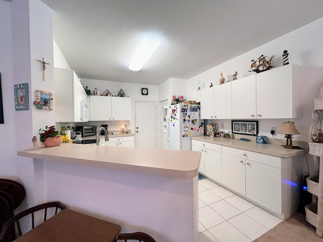 kitchen featuring white cabinetry, white appliances, kitchen peninsula, and a breakfast bar