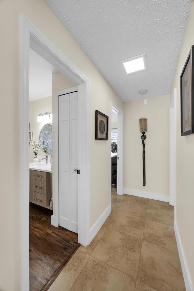 hall featuring a textured ceiling and light tile patterned floors