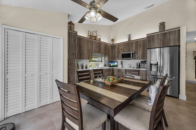 kitchen featuring dark brown cabinets, light tile patterned floors, appliances with stainless steel finishes, ceiling fan, and decorative backsplash