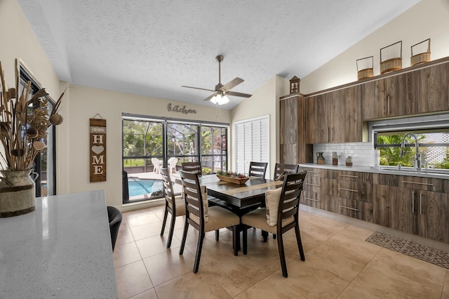 dining room with lofted ceiling, sink, light tile patterned floors, ceiling fan, and a textured ceiling