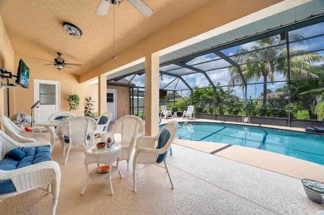 view of swimming pool featuring ceiling fan, a patio, and glass enclosure