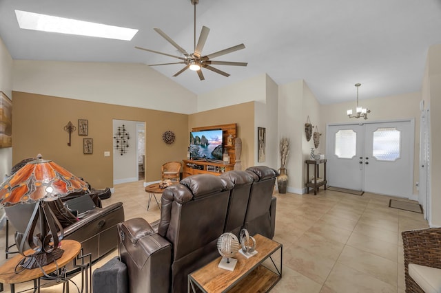 tiled living room with ceiling fan with notable chandelier, lofted ceiling with skylight, and french doors