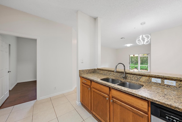 kitchen featuring sink, light stone counters, decorative light fixtures, light tile patterned flooring, and dishwasher