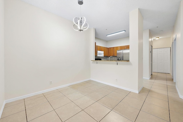 interior space with decorative light fixtures, a notable chandelier, light tile patterned floors, and stainless steel fridge with ice dispenser