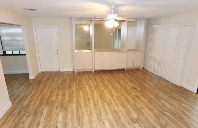 unfurnished room with a textured ceiling, light hardwood / wood-style flooring, and ceiling fan