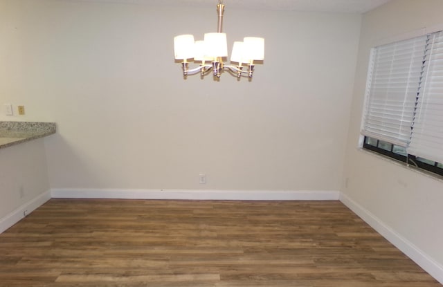 unfurnished dining area with hardwood / wood-style flooring and a notable chandelier