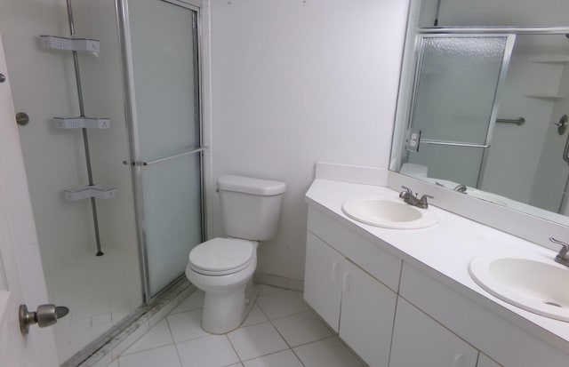 bathroom featuring double vanity, tile patterned floors, toilet, and a shower with door