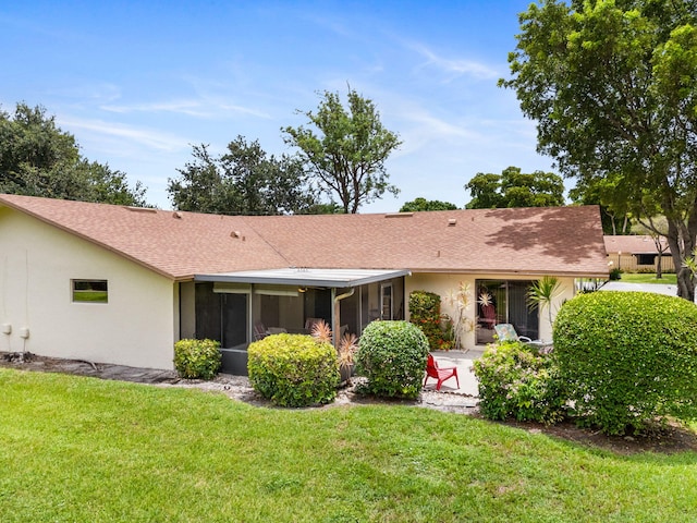 rear view of house featuring a yard and a sunroom