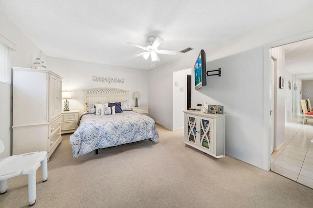 carpeted bedroom featuring ceiling fan and a textured ceiling