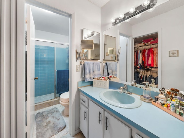 bathroom featuring toilet, tile patterned flooring, vanity, and a shower with door