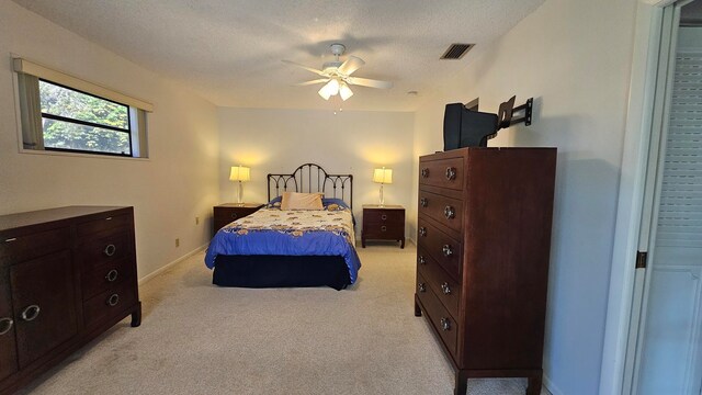 carpeted bedroom with ceiling fan and a textured ceiling