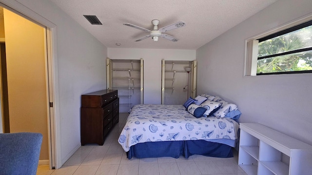 tiled bedroom with a textured ceiling and ceiling fan