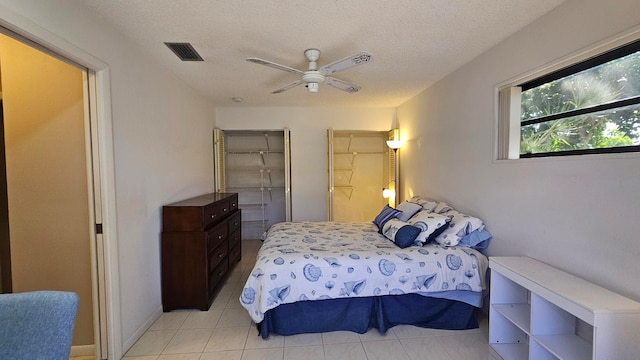 tiled bedroom featuring ceiling fan and a textured ceiling