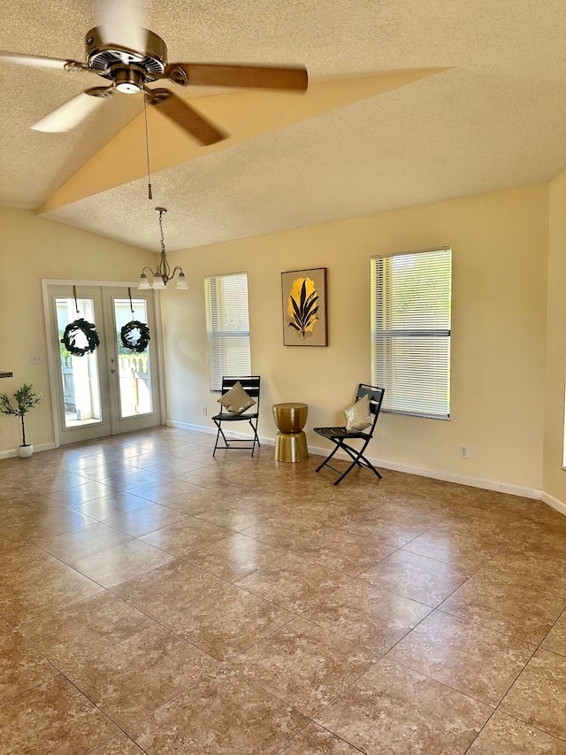 unfurnished room featuring ceiling fan with notable chandelier, lofted ceiling, and french doors