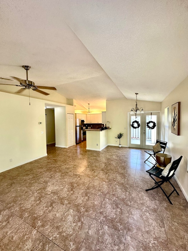 unfurnished living room with a textured ceiling, ceiling fan with notable chandelier, lofted ceiling, and french doors