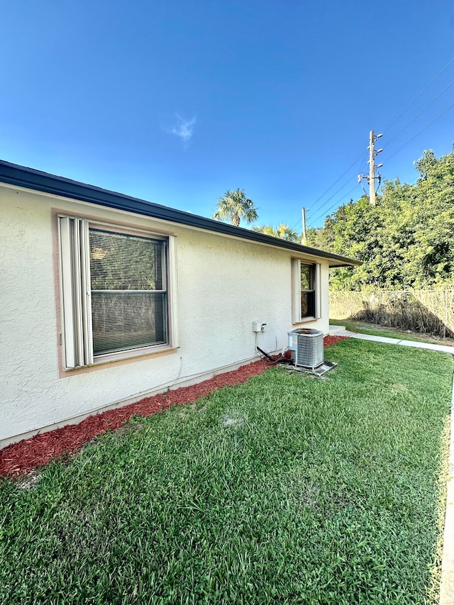 view of side of home featuring central AC and a yard