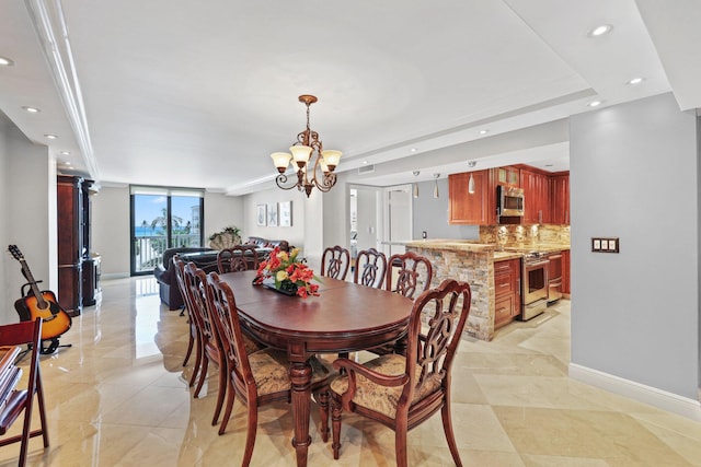 dining room featuring a tray ceiling, a wall of windows, light tile patterned floors, and a chandelier