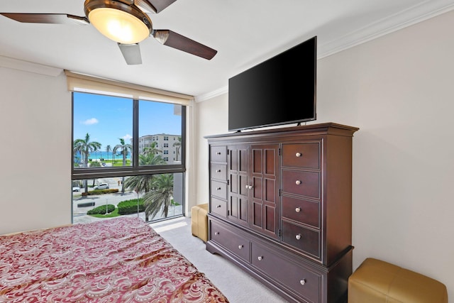 carpeted bedroom with crown molding, expansive windows, and ceiling fan