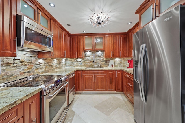 kitchen with tasteful backsplash, stainless steel appliances, sink, light stone countertops, and light tile patterned floors