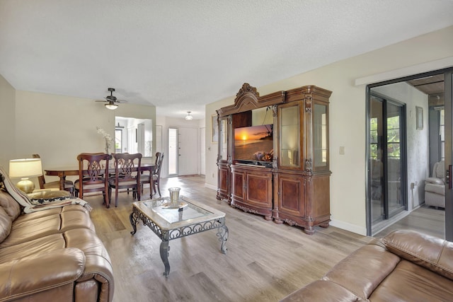 living room with light wood-type flooring, ceiling fan, a wealth of natural light, and a textured ceiling