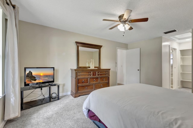 bedroom featuring light carpet, a textured ceiling, and ceiling fan