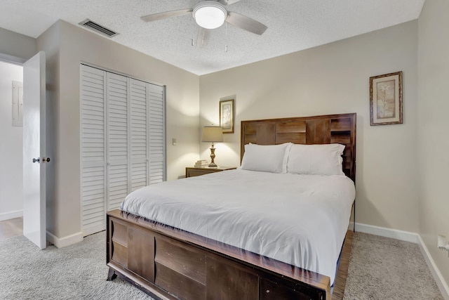 carpeted bedroom with a textured ceiling, ceiling fan, and a closet