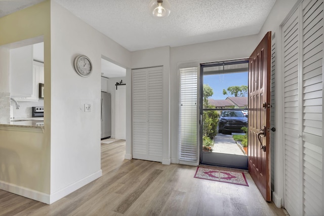 entrance foyer with sink, a textured ceiling, and light wood-type flooring