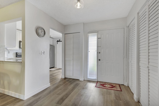 entryway with light hardwood / wood-style floors, sink, and a textured ceiling