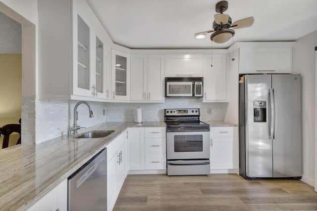 kitchen featuring stainless steel appliances, sink, light hardwood / wood-style floors, backsplash, and ceiling fan