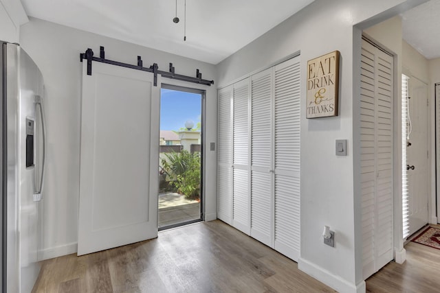 foyer entrance featuring a barn door, a healthy amount of sunlight, and light wood-type flooring