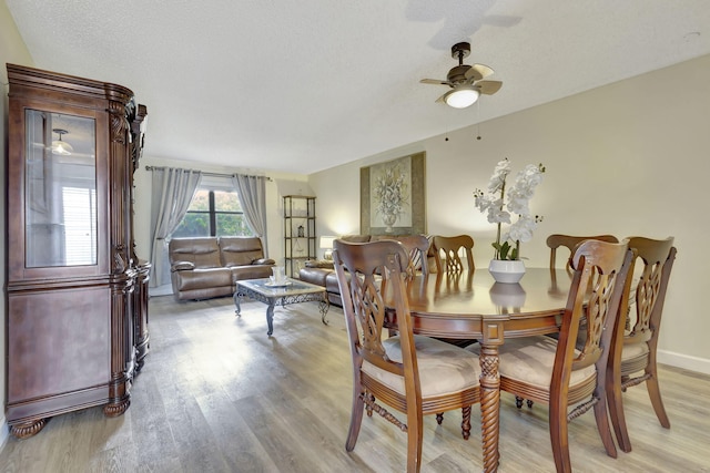 dining space with a textured ceiling, ceiling fan, and light wood-type flooring