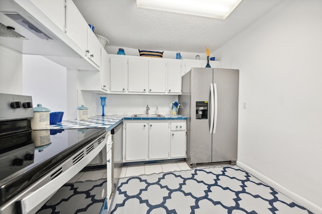 kitchen with stainless steel appliances, white cabinets, sink, a textured ceiling, and light tile patterned floors