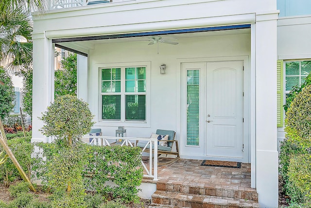 view of exterior entry featuring ceiling fan and a porch